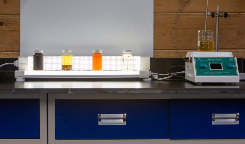 Oil samples lined up beside lab testing equipment