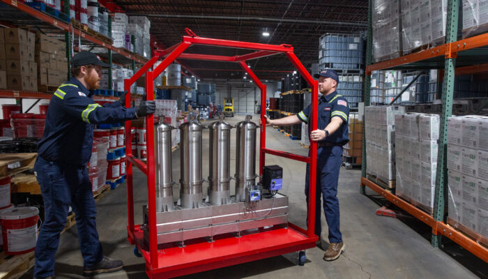 Two Kimbro technicians with a red filtration cart in the warehouse