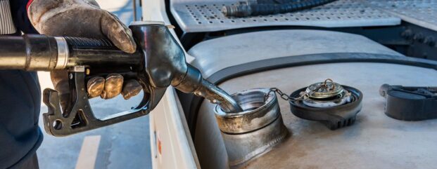 Technician using a dispensing nozzle to fill an equipment tank