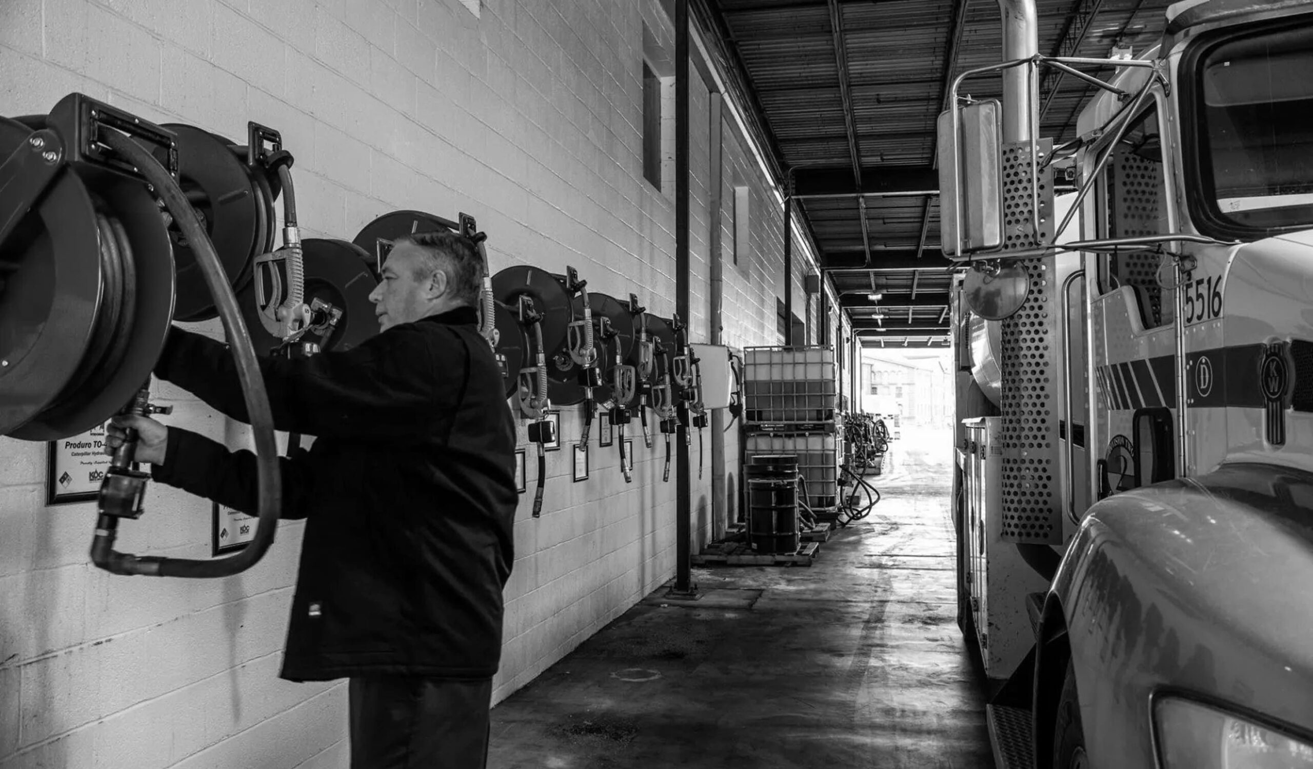 Black-and-white photo of a Kimbro employee at lubricant hose reels