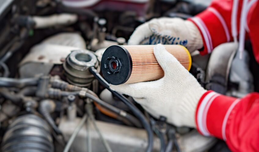 Mechanic holding an oil filter over an engine
