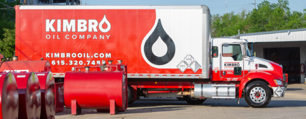 Kimbro Oil Company box truck beside red fuel tanks