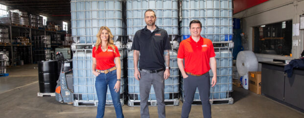 Three Kimbro employees standing in front of stacked totes in the warehouse